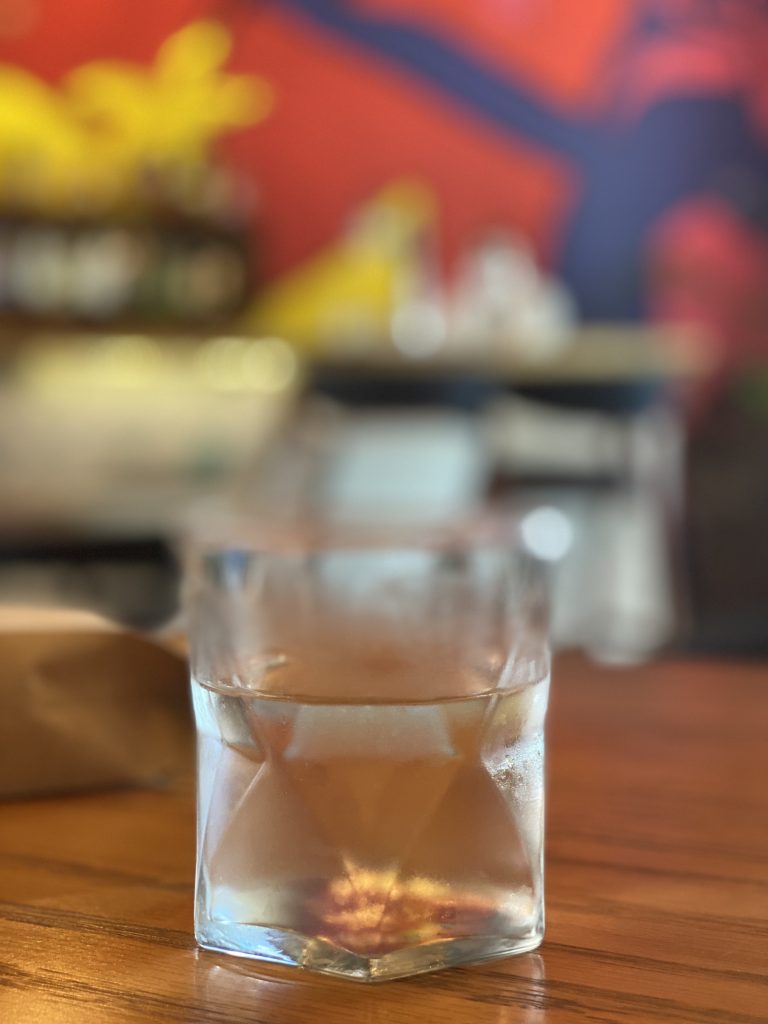 glass with water, on a table, blurry colorful background
